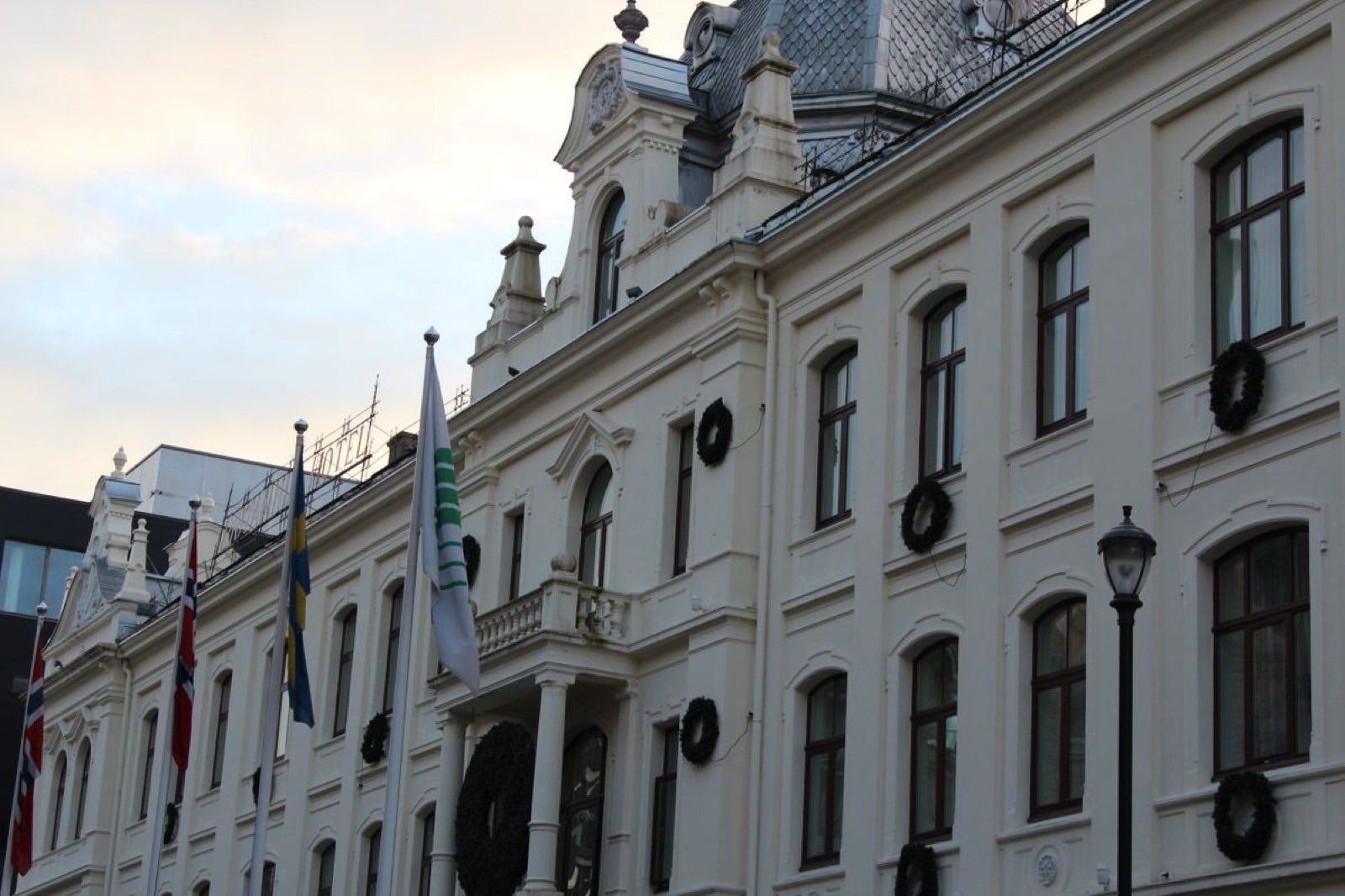 Pusset hotellfasade med flaggstenger, gesimser og kransedekor