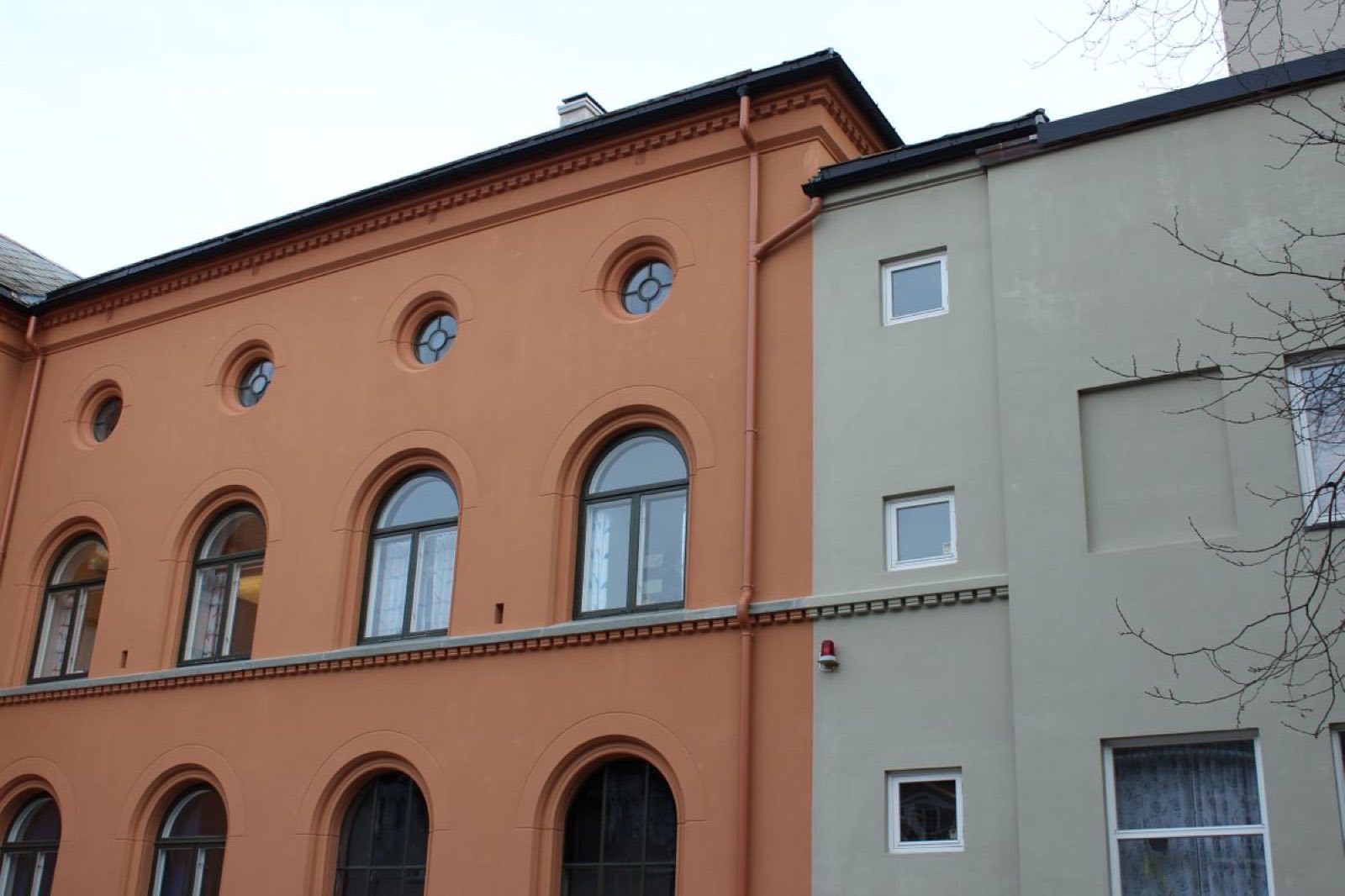 Terrakottafarget murfasade med buede vindusomramminger